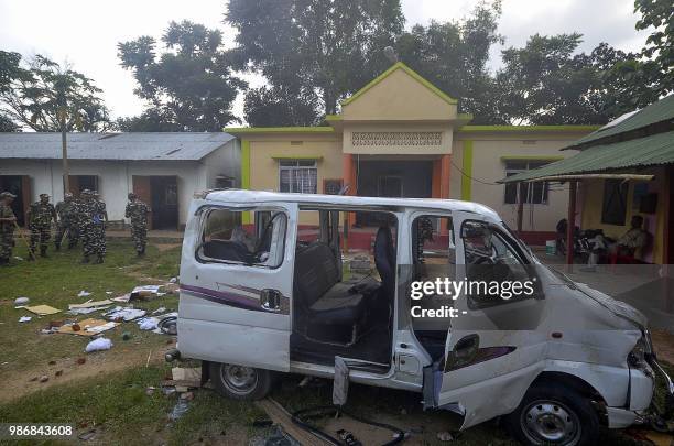 Indian paramilitary force personnel keep vigil near a damaged vehicle after an angry mob lynched one person and injuring others at a makeshift in...