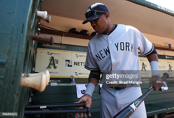 Marcus Thames of the New York Yankees puts bats in the bat rack in the dugout before the game between the New York Yankees and the Oakland Athletics...