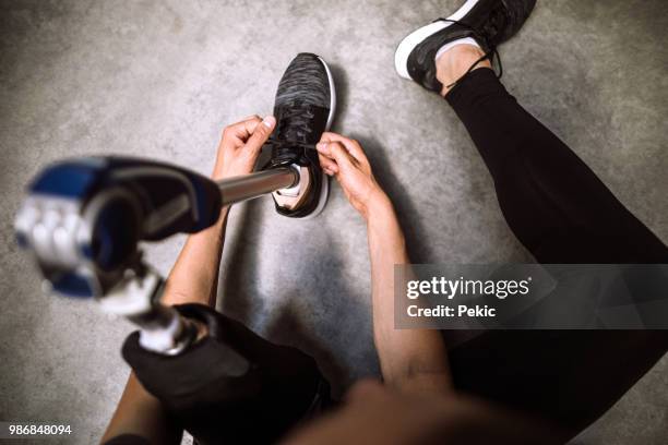atleta amputado atar sus cordones de zapato antes de entrenamiento deportivo - atletismo en pista masculino fotografías e imágenes de stock