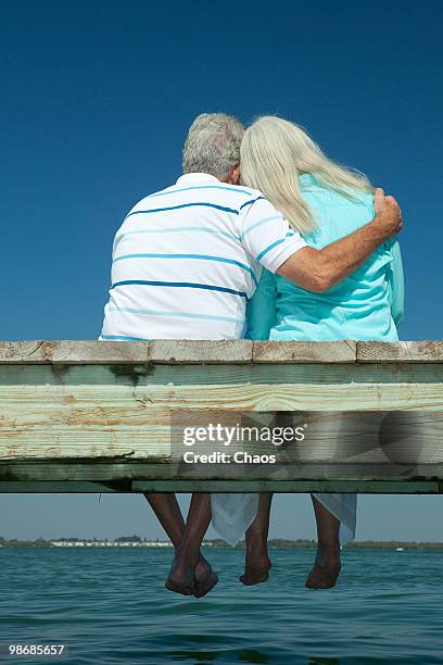 cuddling older couple sitting on a boat dock - anna maria island foto e immagini stock