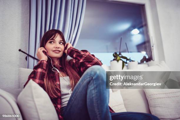 attractive female listening to music while relaxing in living room - the soundtrack of my life stock pictures, royalty-free photos & images