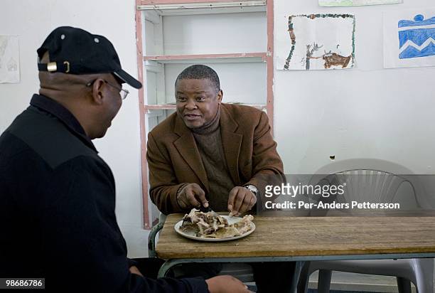 Zaki Makozoma , a businessman, chats to a friend while he eats on June 28 at the yearly arts festival in Grahamstown, South Africa. Mr. Macozoma, was...