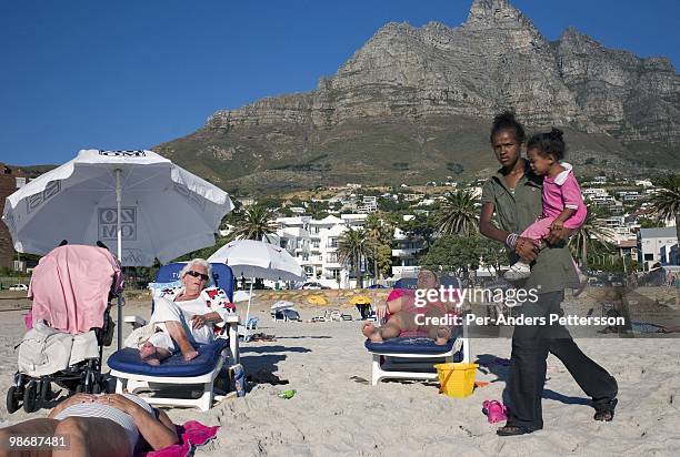 Wealthy tourists enjoy the beach as the sun sets on March 20, 2009 in Camps Bay, a posh sea side resort in Cape Town, South Africa. Camps Bay is one...