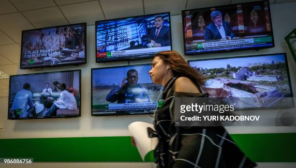 Picture taken on June 8, 2018 shows a journalist of the Russia Today TV company as the walks past monitors in their corridor in Moscow.