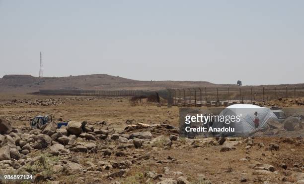 Syrian families are seen near the Golan Heights and the Israel-Jordan border after they fled from the ongoing military operations by Bashar al-Assad...