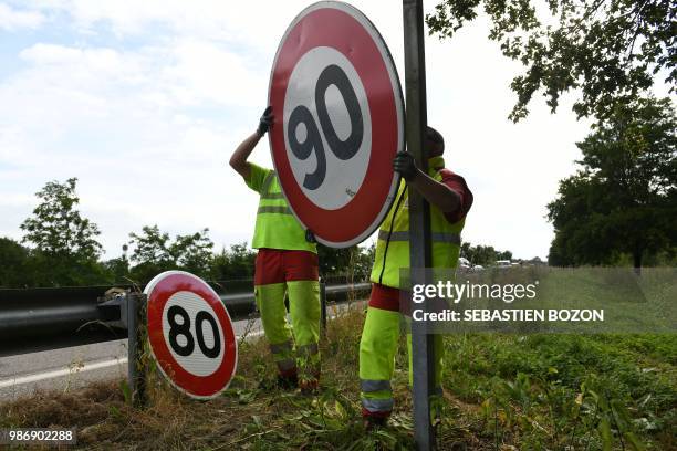 Employees of DIR Est replace a 90 Km/h speed limit sign with an 80 Km/h one on a road on June 29, 2018 in Wittenheim eastern France. - As of July 1,...