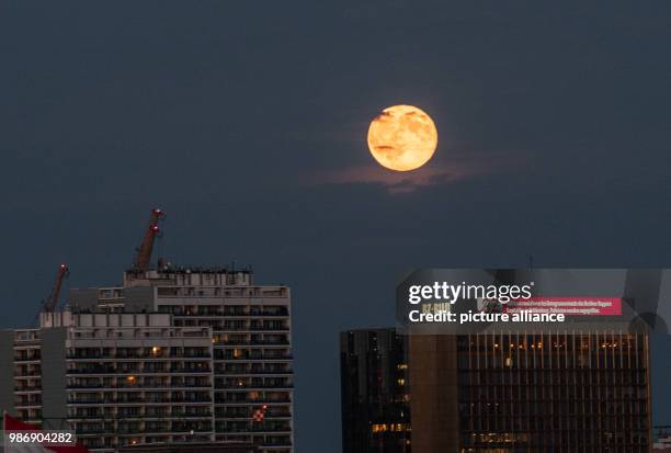 June 2018, Germany, Berlin: The moon rises over the Axel Springer high-rise building. Photo: Paul Zinken/dpa