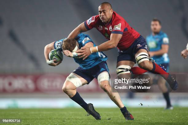 Blake Gibson of the Blues is tackled by Caleb Timu of the Reds during the round 17 Super Rugby match between the Blues and the Reds at Eden Park on...