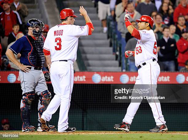 Bobby Abreu of the Los Angeles Angels of Anaheim celebrates his two-run homerun with Brandon Wood as catcher Mike Redmond of the Cleveland Indians...
