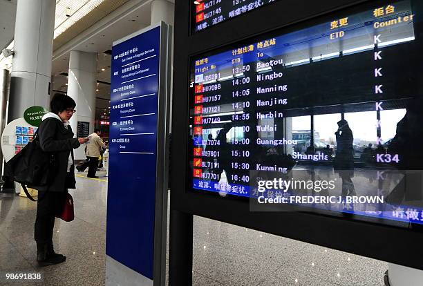 Traveller checks her ticket beside a flight departures screen at Beijing's Capital International Airport, Terminal 1, on April 27, 2010. US-based...