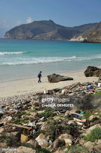 sultanate of oman, dhofar, a man is walking on a wild beach full of rubbish at the west of salalah - dhofar stock pictures, royalty-free photos & images