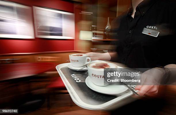 An employee carries a tray of coffees at a Costa Coffee shop in London, U.K., on Monday, April 26, 2010. Whitbread Plc., which own Costa Coffee,...