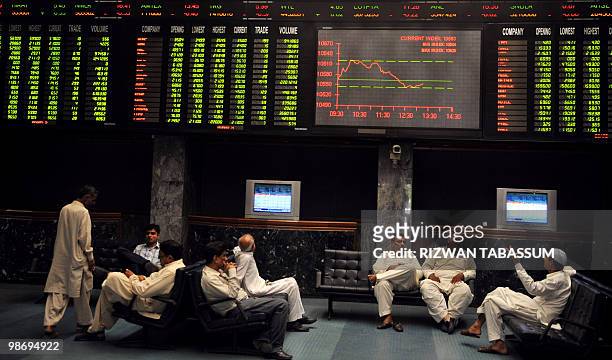 Pakistani men discuss under the share prices digital board during a trading session at the Karachi Stock Exchange on April 27, 2010.The benchmark...