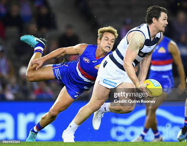 Patrick Dangerfield of the Cats handballs whilst being tackled by Mitch Wallis of the Bulldogs during the round 15 AFL match between the Western...