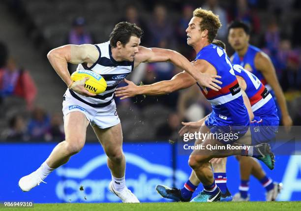 Patrick Dangerfield of the Cats fends off a tackle by Mitch Wallis of the Bulldogs during the round 15 AFL match between the Western Bulldogs and the...