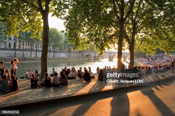 france, paris, picnickers on the bank of the seine, at the end of the day. - river seine foto e immagini stock