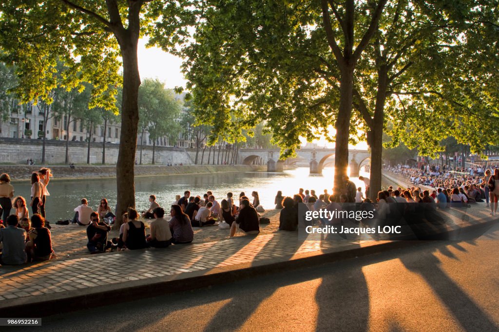 France, Paris, picnickers on the bank of the Seine, at the end of the day.