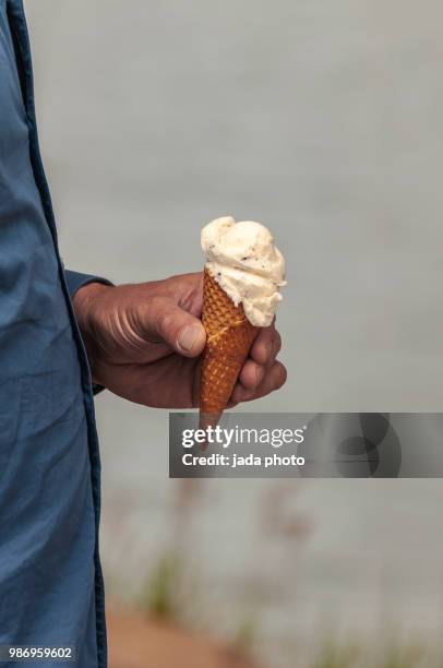 a man holds a ice cream cone in his hand - icehorn stock pictures, royalty-free photos & images