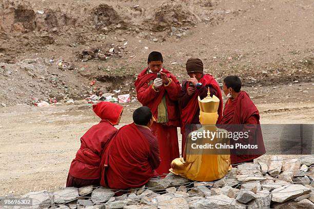 Tibetan monks take a photo of a Buddhist Sculpture at the Changu Temple of Jiegu Township on April 25, 2010 in Yushu County of Qinghai Province,...