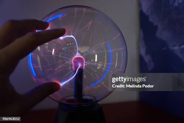 hand touching a plasma ball at a science museum - plasma ball foto e immagini stock