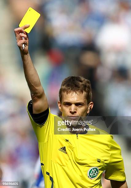 Referee Jochen Drees shows the yellow card during the Bundesliga match between Hertha BSC Berlin and FC Schalke 04 at the Olympic stadium on April...