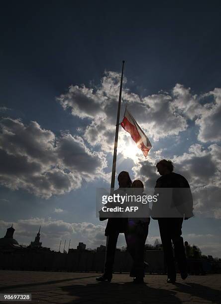 People walk by a Polish flag on the Pilsudski place in Warsaw on April 15, 2010 in memory of 96 people who died in an aircrash on April 10. Late...