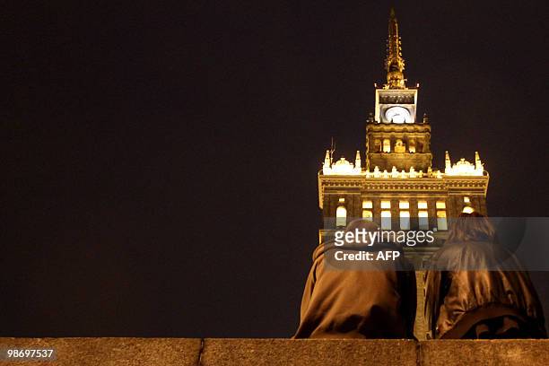 Couple is watching a group of people protesting against the plan to burry the late Polish presidential couple in Cracow's Wawel castle, in front of...