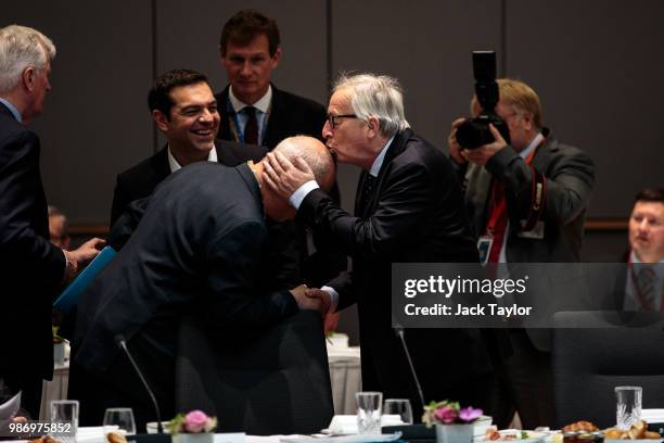 President of the European Commission Jean-Claude Juncker kisses a man's head as Prime Minister of Greece Alexis Tsipras looks on ahead of roundtable...