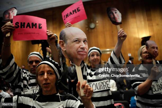 Demonstrators from Code Pink for Peace hold photographs of Lloyd Blankfein, chairman and CEO of The Goldman Sachs Group, and demand he be jailed with...