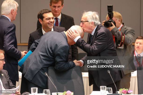 Greece's Prime Minister Alexis Tsipras looks at President of the European Commission Jean-Claude Juncker kissing the head of a sit the head of an...