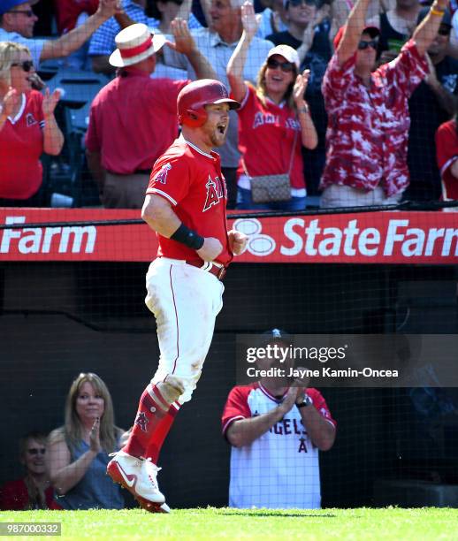 Kole Calhoun of the Los Angeles Angels of Anaheim celebrates after scoring the a run to tie the game on a double by Martin Maldonado of the Los...