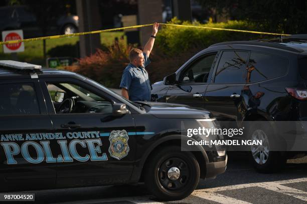 An Anne Arundel County, Maryland, police officer guards a closed street leading to the Capital Gazette newspaper offices in Annapolis on June 29,...