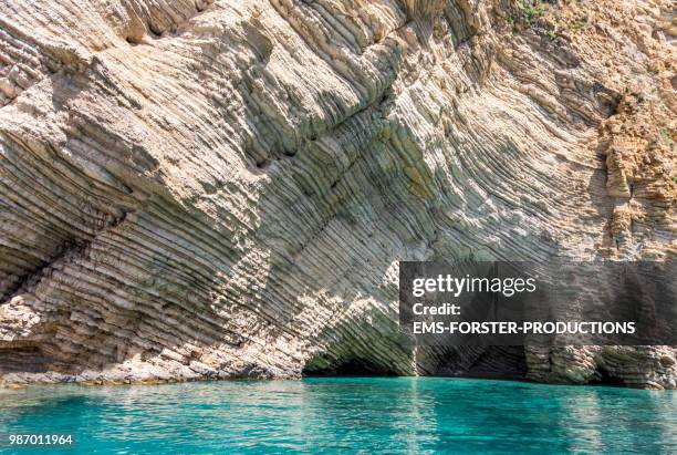 septate cliff rock background with green - turquoise sea water in foreground - strate géologique photos et images de collection