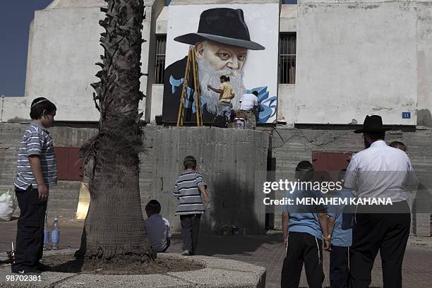 Ultra orthodox Jews look at Spanish graffiti artists working on a large spray painted portrait of the Lubavitcher Rabbi, Menachem Mendel Schneerson,...