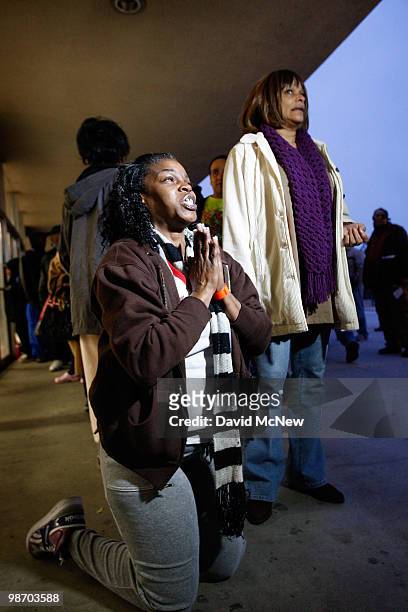 Leticia Brown kneels to express her joy and thankfulness for the opportunity to receive badly needed dental care as she waits in line for free...