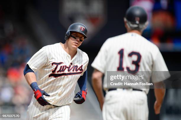 Third base coach Gene Glynn of the Minnesota Twins waits to congratulate Logan Morrison as he rounds the bases after hitting a home run against the...