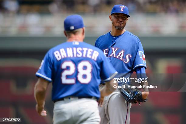 Yovani Gallardo of the Texas Rangers reacts as manager Jeff Banister walks out to the mound during the game against the Minnesota Twins on June 23,...