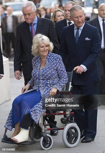 Prince Charles, Prince of Wales pushes Camilla, Duchess of Cornwall in a wheel chair as they arrive for the Premiere of 'Aida' at the Royal Opera...