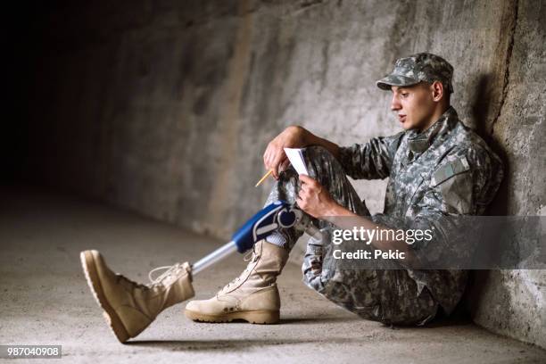 young amputee soldier sitting in bunker alone - military bunker stock pictures, royalty-free photos & images