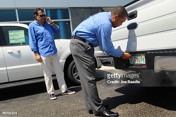 Ford salesman, Ted Warburton, places new plates on the Ford pick up that Giancarlo Lasio bought from Metro Ford on April 27, 2010 in Miami, Florida....