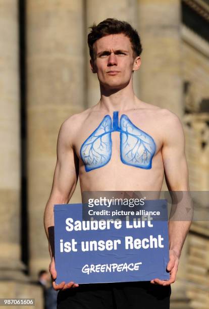 February 2018, Germany, Leipzig: An environmental activist carries the sign reading 'Saubere Luft ist unser Recht' during a rally in front of the...