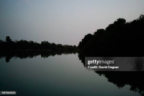 Calm photo of The Gambia River at Dusk in Basse Santé Su, The Gambia. At sunset many birds come out and can be seen traversing the river.