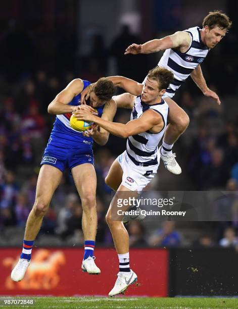 Marcus Bontempelli of the Bulldogs marks infront of Jake Kolodjashnij and Jed Bews of the Cats during the round 15 AFL match between the Western...