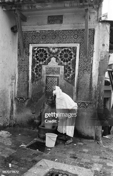 Une femme tire de l'eau à une fontaine de la Casbah d'Alger le 09 avril 1975.