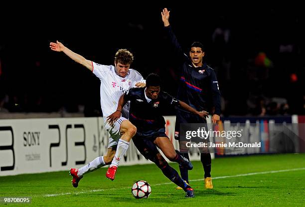 Michel Bastos of Olympique Lyonnais is tackled by Thomas Muller of Bayern Muenchen during the UEFA Champions League semi final second leg match...