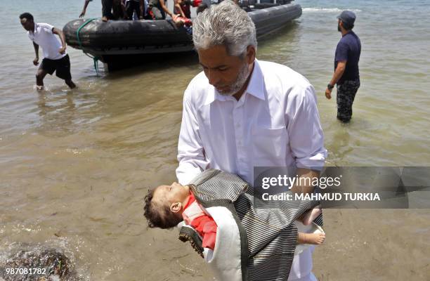 Graphic content / A man carries the body of a baby as migrants who survived the sinking of an inflatable dinghy boat off of the coast of Libya are...