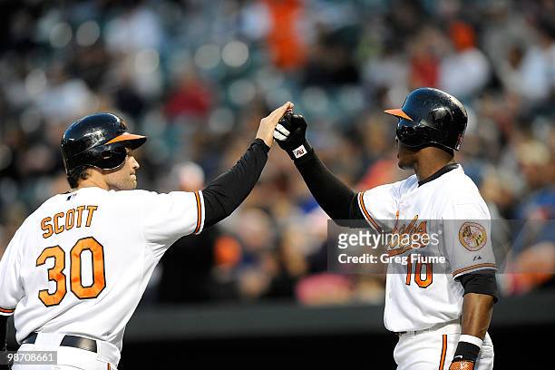 Luke Scott of the Baltimore Orioles is congratulated by Adam Jones after scoring in the second inning against the New York Yankees at Camden Yards on...