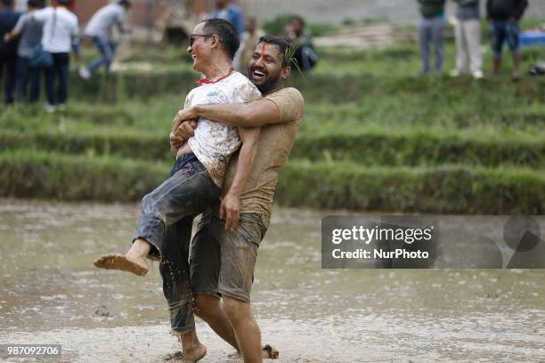 Nepalese play in the mud water at paddy field during National Paddy Day or Asar Pandra, which marks the commencement of rice crop planting in paddy...