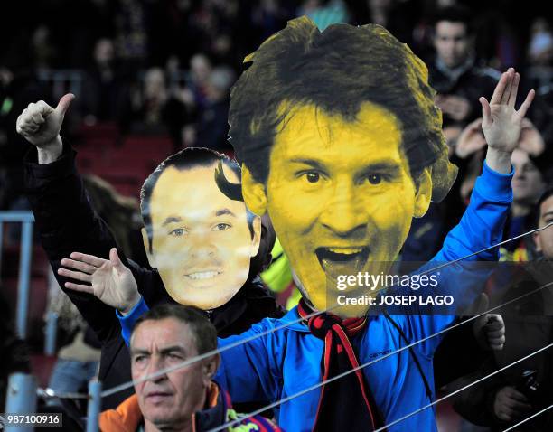 Barcelona FC's fan with a giant mask of Barcelona's Argentinian forward Lionel Messi made with cardboard flanked by a masked fan of Barcelona's...