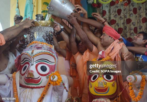 Hindu priests pour milk over a statue of Jagannath during the Snana Yatra procession. The Snana Yatra is a bathing festival celebrated on the Purnima...